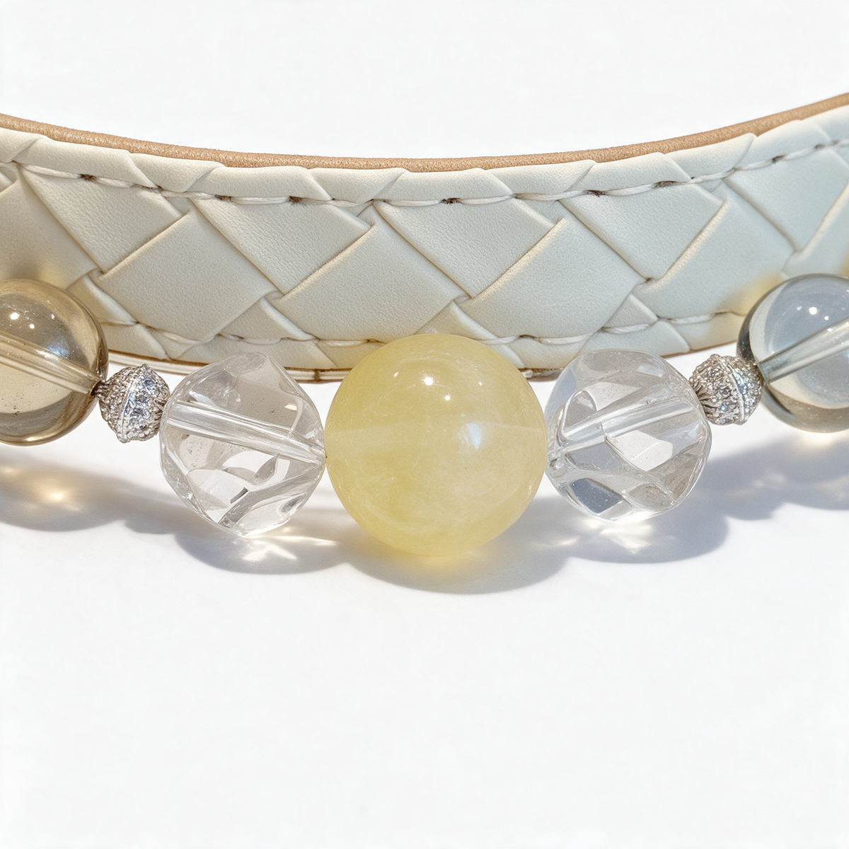 Macro view of the Lemon Daylight collar, showing its yellow center, clear irregular beads, silver-tone accents and cream diamond-stitched band.