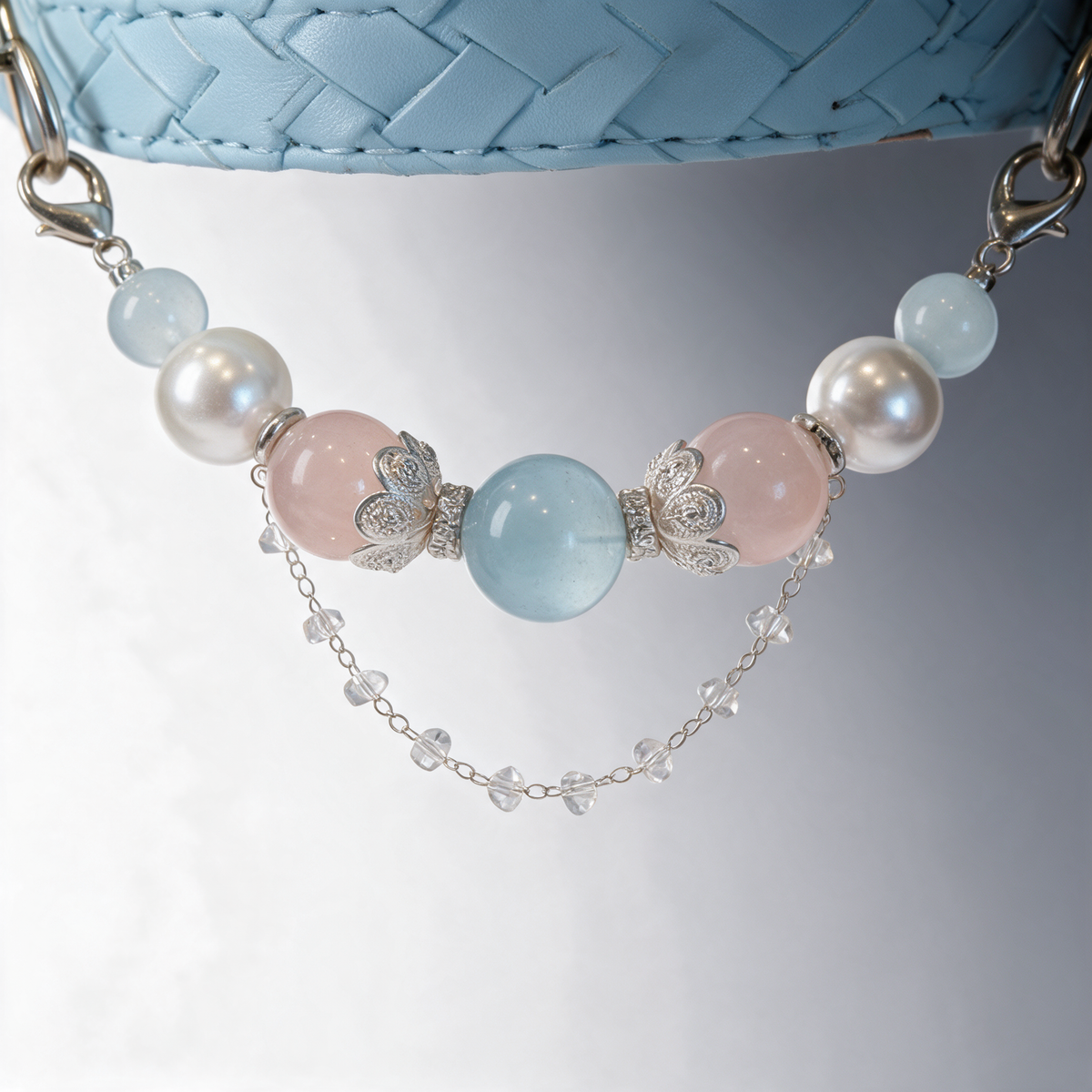 Close view of the Coastal Blush collar with blue and pink beads, silver-tone floral caps and a delicate crystal-accented chain.