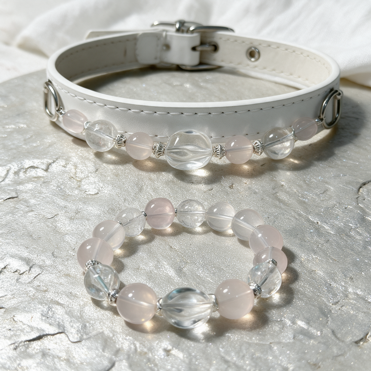 Close view of the Blush Whisper collar and matching owner bracelet, showing the pale pink and clear beads and white stitched band.