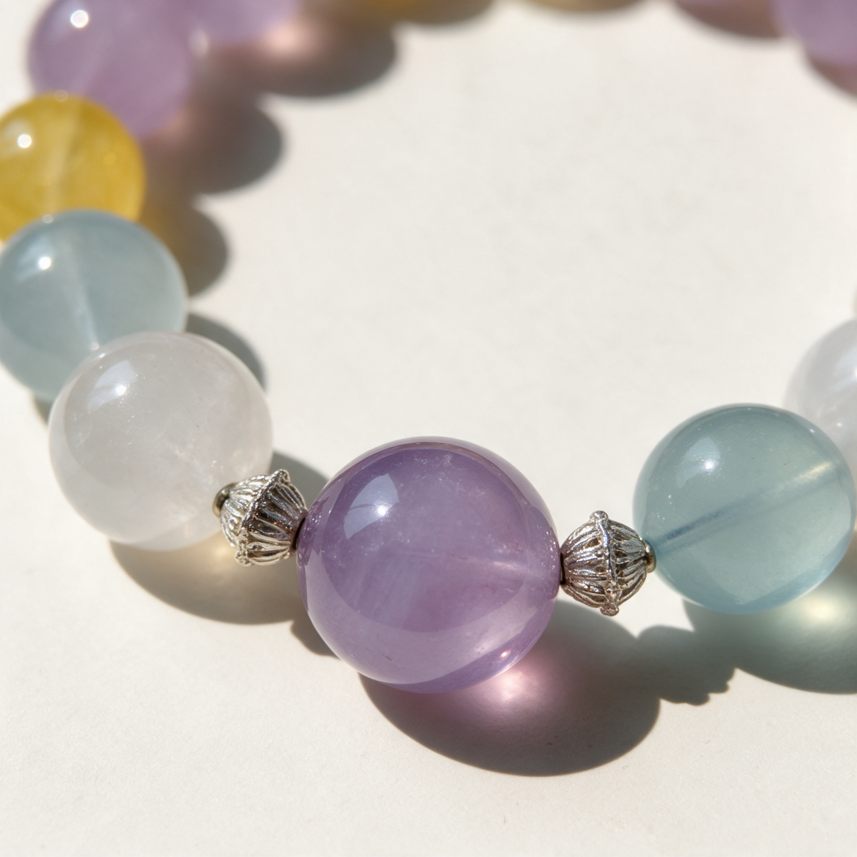 Close-up of the Pastel Morning bracelet with a purple focal bead, silver-tone spacers and neighboring pale blue and white beads.