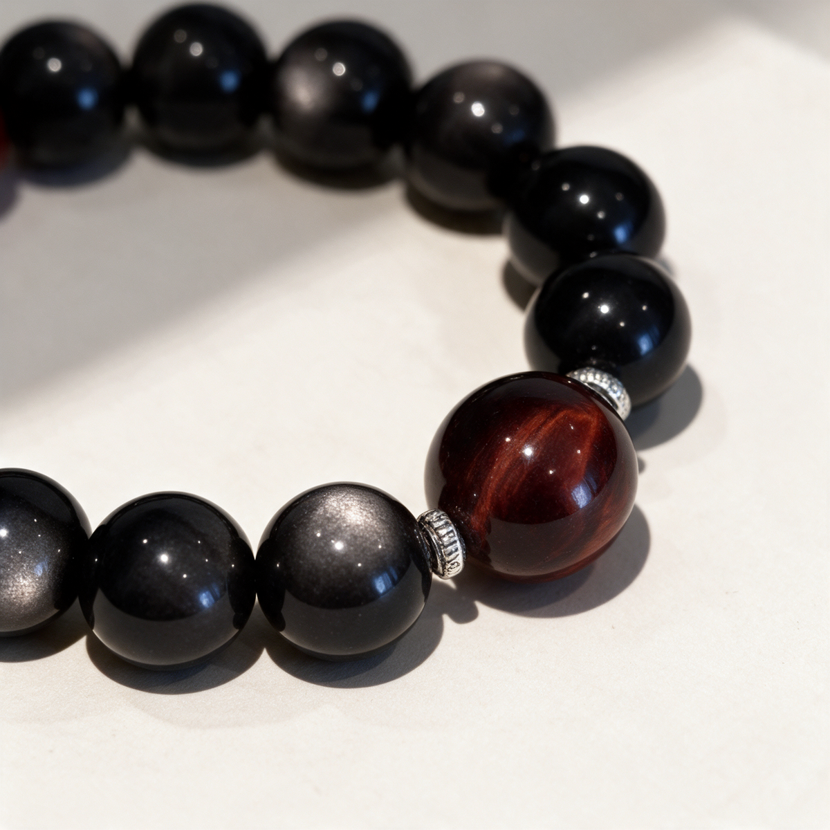 Close-up of the Crimson Bond bracelet’s red-brown focal bead, silver-tone spacers and black crystal beads.