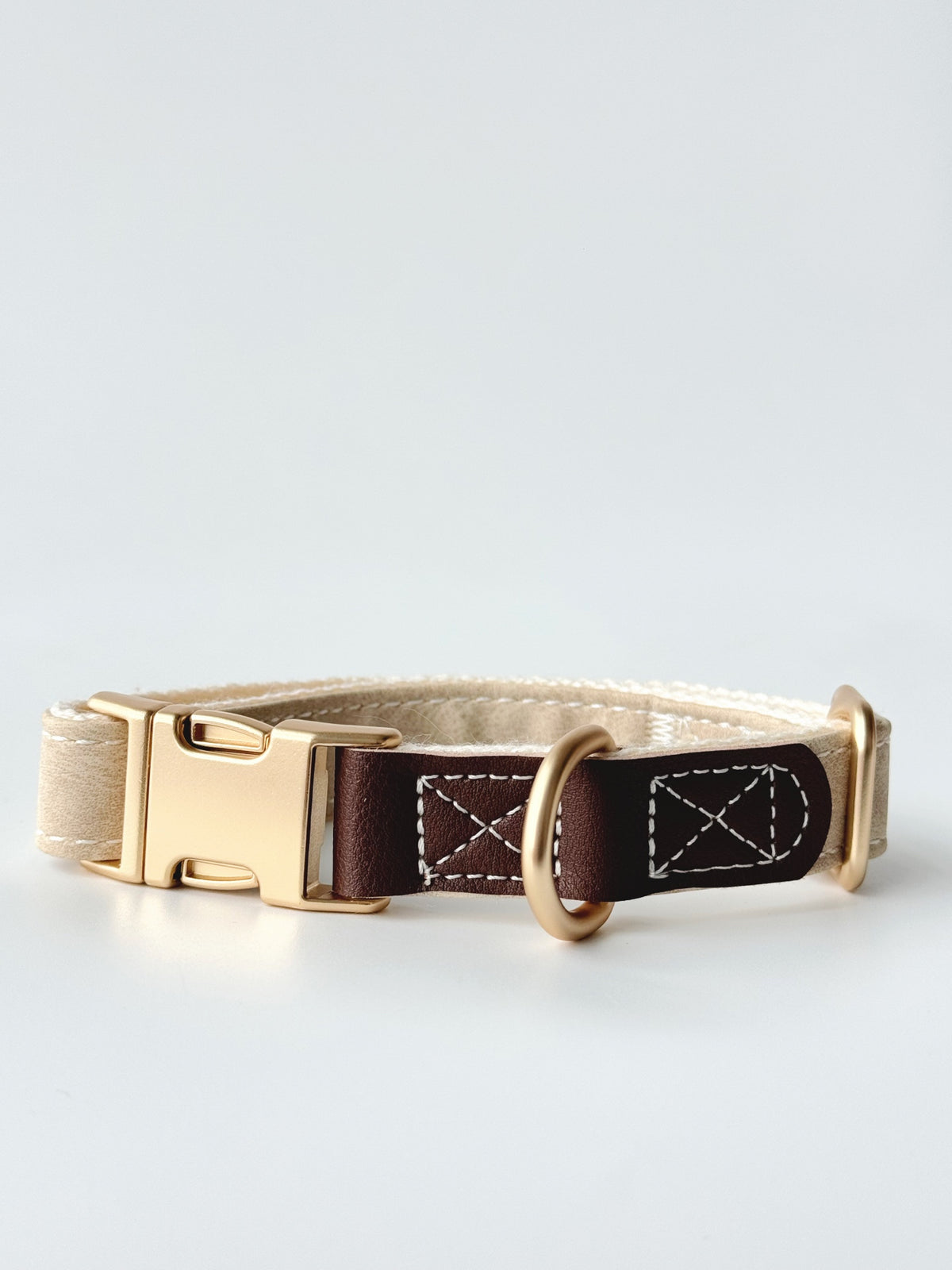 Cream buckle collar hardware detail. Every size includes five selectable charms; extra charms and leash sold separately.